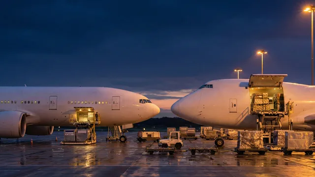 Comparison of belly cargo hold in a passenger aircraft versus a fully loaded dedicated freighter aircraft on a dusk tarmac